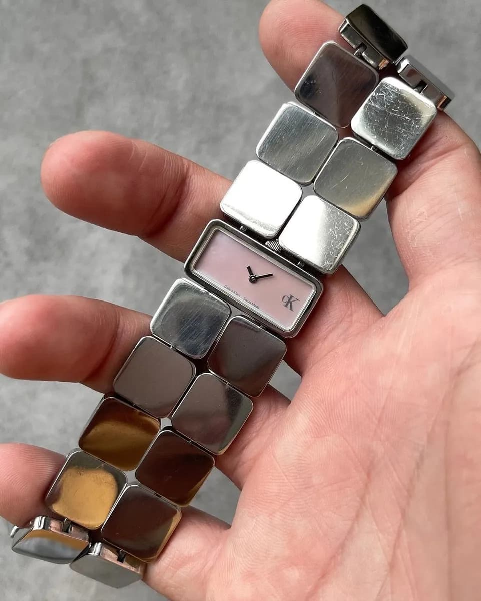Steel tile-link Calvin Klein watch with a pink dial held in a hand