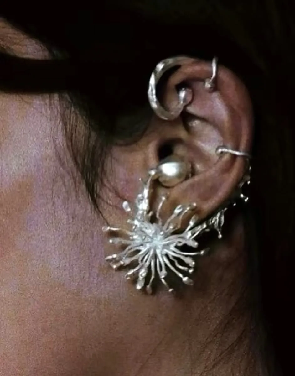 Silver sea anemone shaped earring with a pearl, worn on an ear